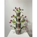 Elegant ceramic piece featuring four stacked vases with geometric patterns, each filled with blooming purple tulips.